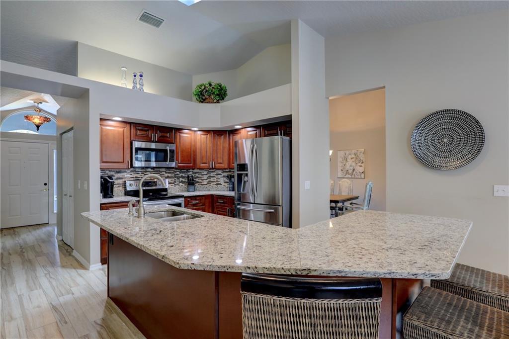 562 Rolling Hill Drive Sebastian, FL 32958 - Photo 17 of 42 a kitchen with granite countertop stainless steel appliances a sink a stove top oven a counter space and cabinets
