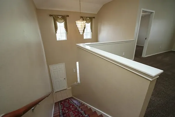 a view of an empty room with chandelier fan and window