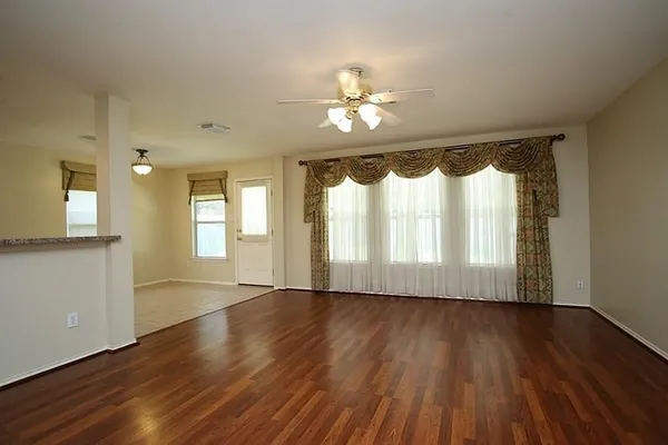 a view of an empty room with wooden floor and a window