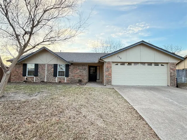 a view of a house with a yard and large tree