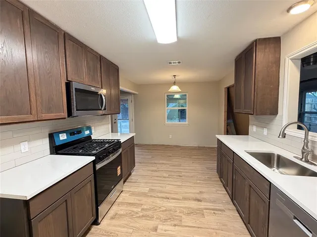 a kitchen with a sink stove top oven and refrigerator