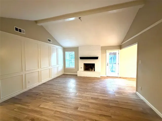 a view of empty room with wooden floor and fireplace