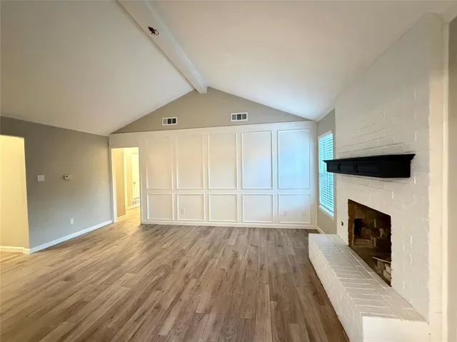 a view of empty room with wooden floor and fireplace