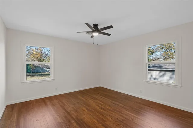 a view of a big room with wooden floor and windows