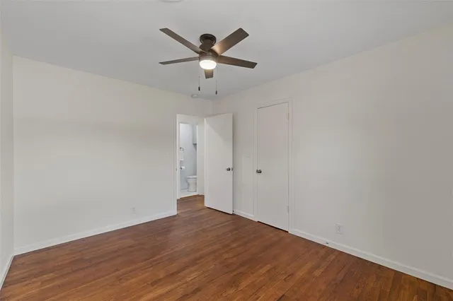 an empty room with wooden floor and ceiling fan