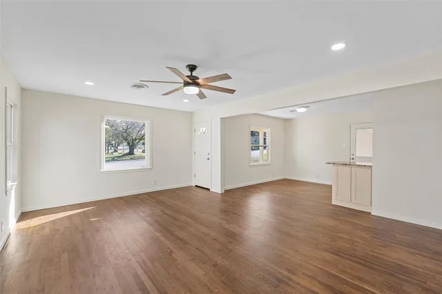 a view of an empty room with a window and wooden floor