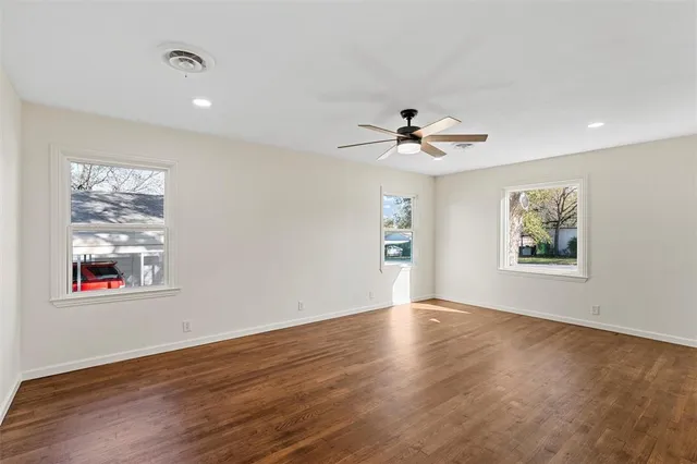 a view of an empty room with a window and wooden floor