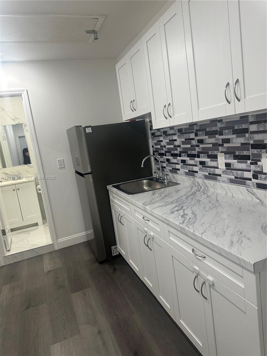 13740 Southwest 282nd Street, Unit 1 Homestead, FL 33033 - Photo 5 of 9 a kitchen with granite countertop white cabinets and refrigerator