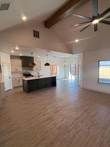 a large kitchen with stainless steel appliances granite countertop a large counter top a stove and a wooden floors