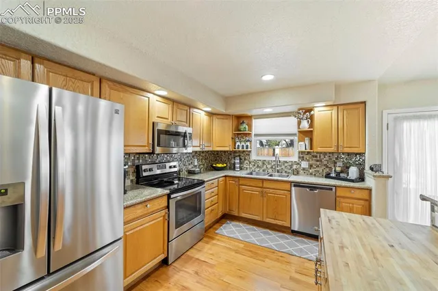 a kitchen with stainless steel appliances granite countertop a refrigerator a stove top oven a sink and dishwasher