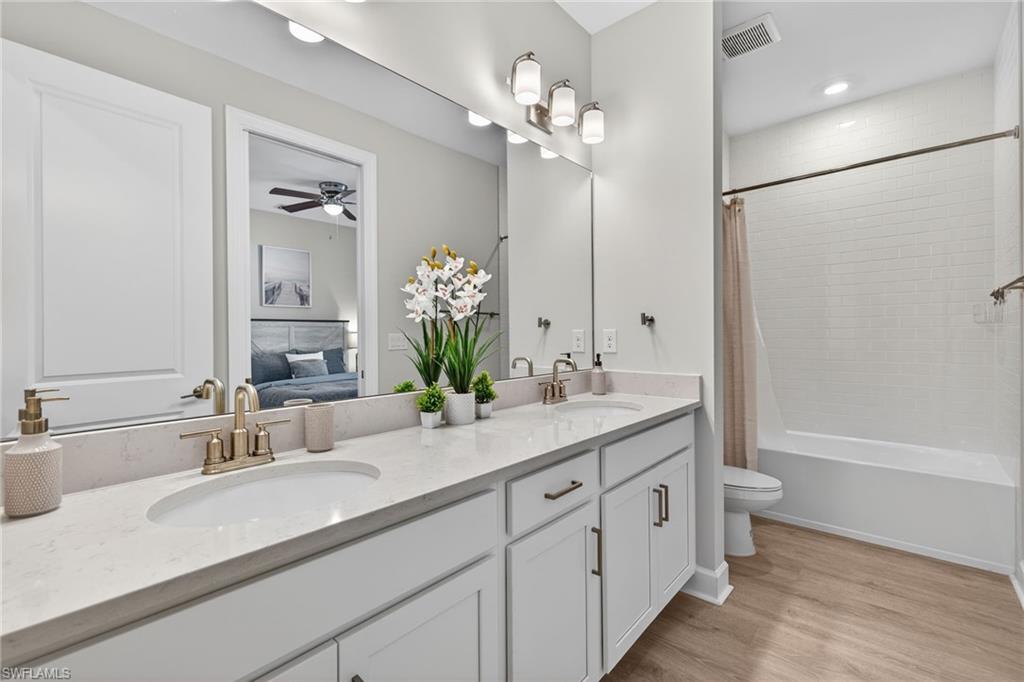 15641 Gavello Street Naples, FL 34114 - Photo 24 of 37 a bathroom with a double vanity sink mirror and toilet