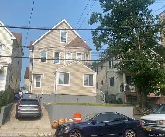 a front view of a house with cars parked on road
