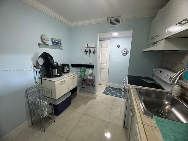 a kitchen with a sink a stove top oven a refrigerator and cabinets