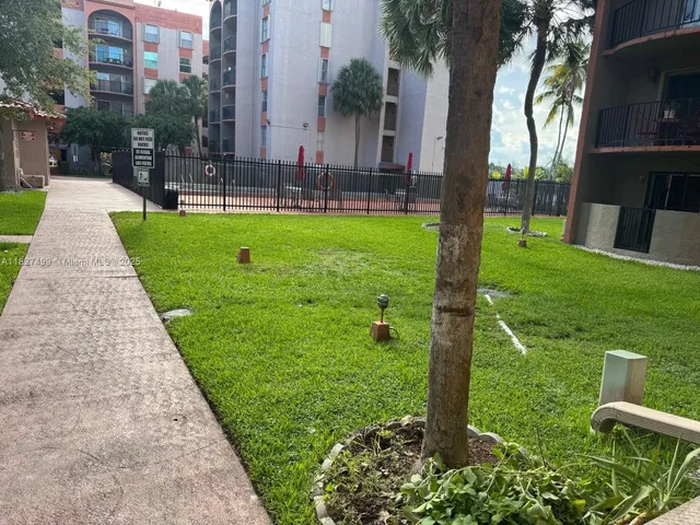 a view of a brick house with a big yard and large trees