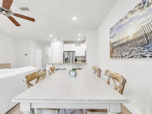 a dining table sitting next to a white wall with white cabinets