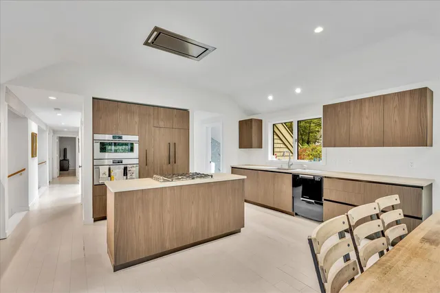 a large kitchen with stainless steel appliances kitchen island granite countertop a refrigerator and a stove top oven