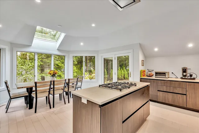 a kitchen with a stove a sink a dining table and chairs with wooden floor
