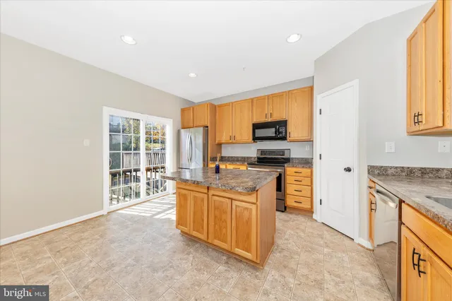 a kitchen with stainless steel appliances granite countertop a stove top oven a sink dishwasher a refrigerator and cabinets with wooden floor