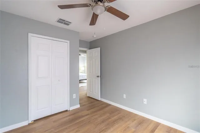 wooden floor in an empty room with a chandelier fan