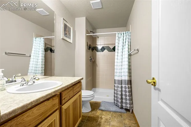 a bathroom with a granite countertop sink a toilet and shower