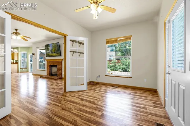 a view of an empty room with wooden floor and a window