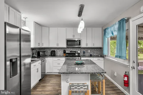 a kitchen with stainless steel appliances granite countertop a refrigerator a sink a stove and white cabinets