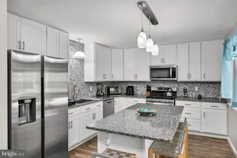 a kitchen with stainless steel appliances granite countertop a sink a refrigerator and microwave
