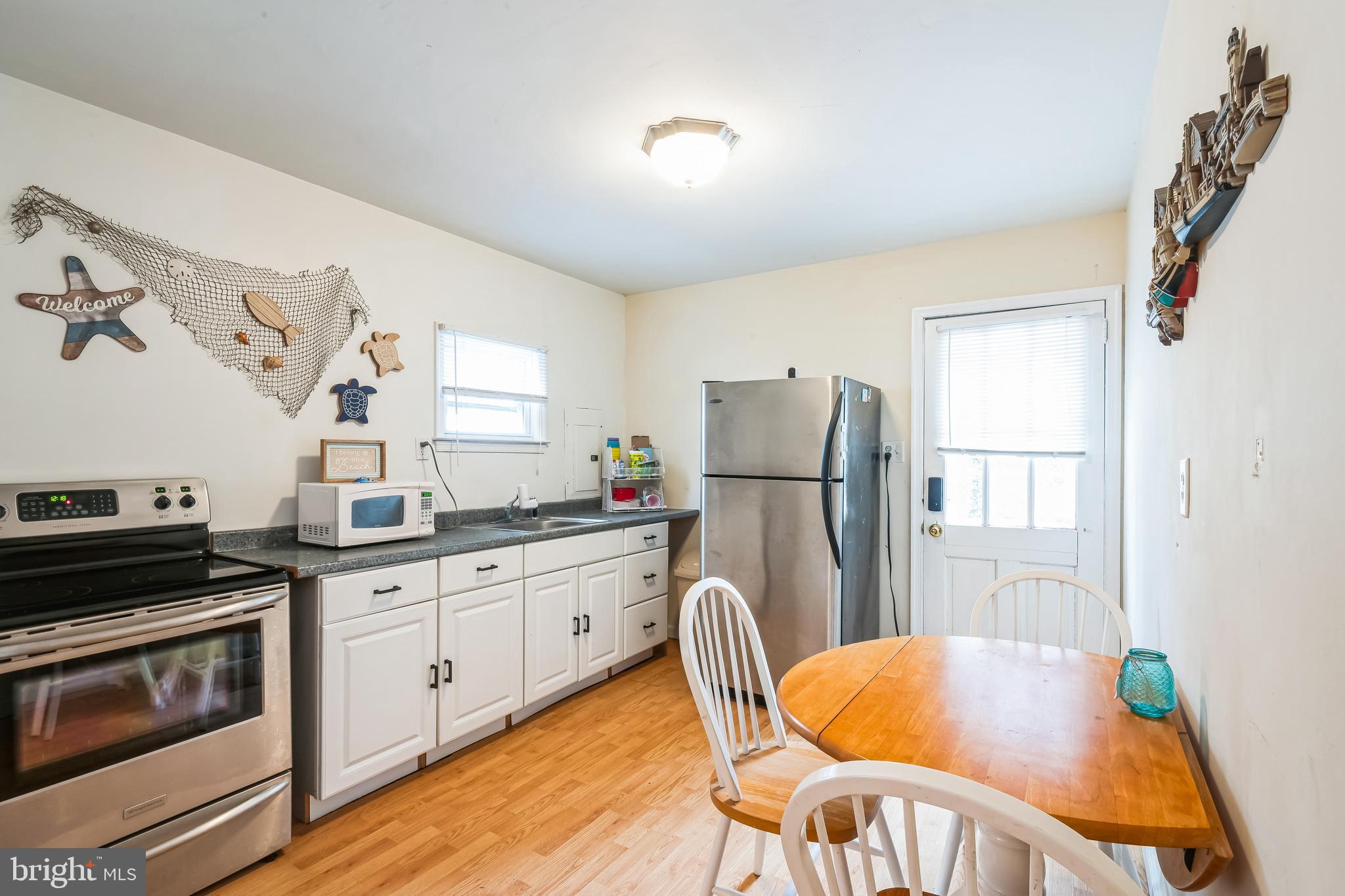 13 Paula Lane Villas, NJ 08251 - Photo 10 of 30 a kitchen with stainless steel appliances granite countertop a stove a refrigerator a dining table and chairs with wooden floor
