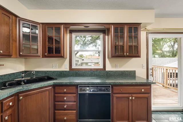 a kitchen with granite countertop a sink window and cabinets