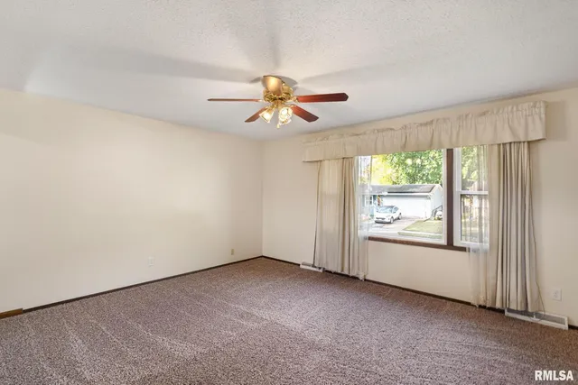 an empty room with windows and chandelier fan
