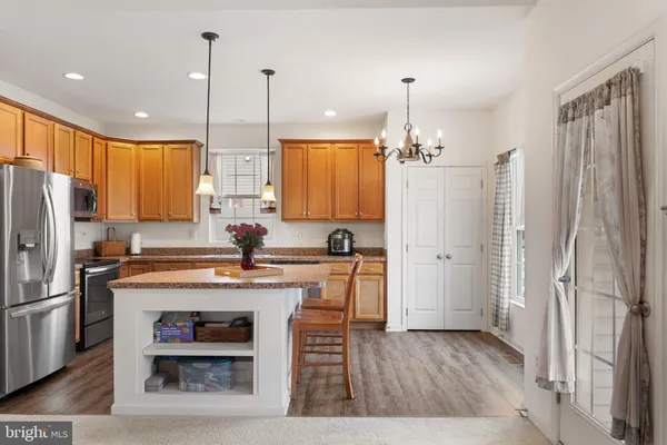 a kitchen with kitchen island granite countertop a stove a sink a refrigerator and a wooden floor