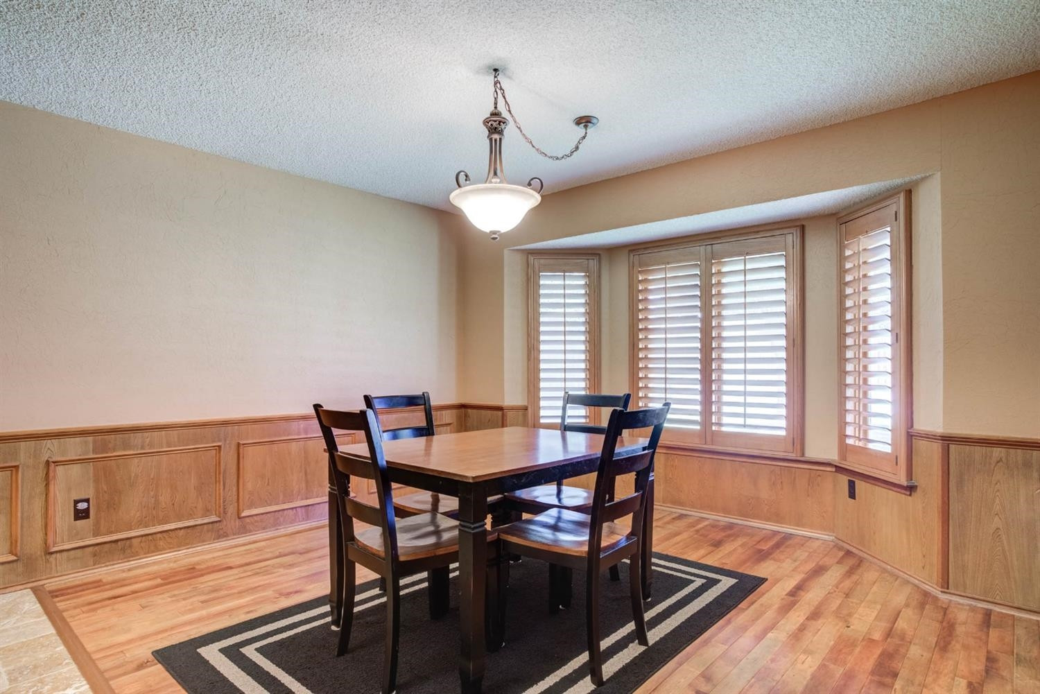 5304 90th Street Lubbock, TX 79424 - Photo 15 of 39 a dining room with wooden floor a chandelier a wooden table and chairs