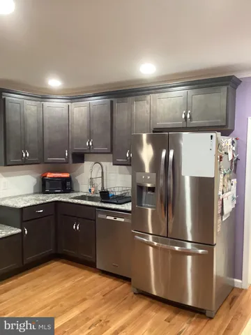 a kitchen with granite countertop a refrigerator and wooden cabinets