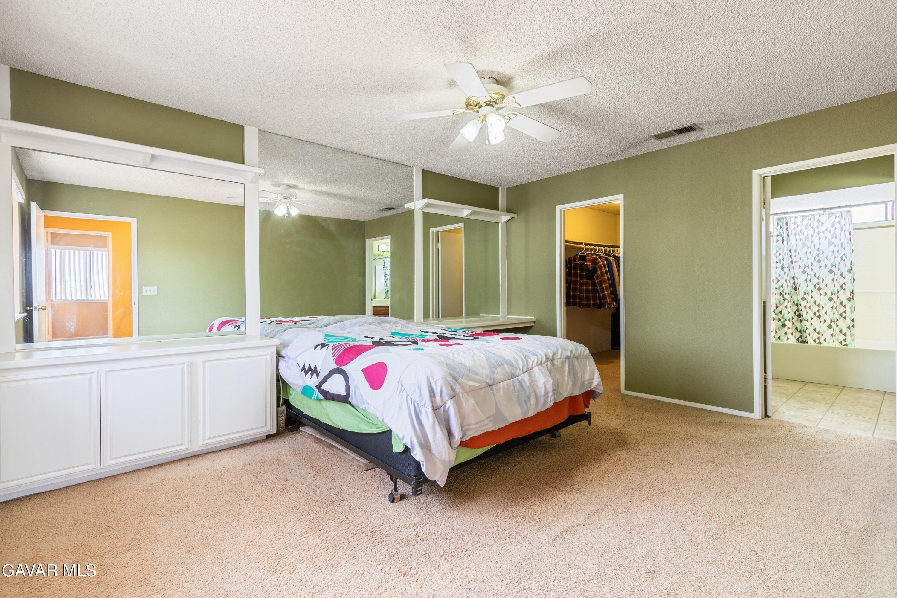 4625 Avenue R6 E Palmdale Ca East Palmdale, CA 93552 - Photo 23 of 25 a spacious bedroom with a bed a mirror on dresser and a large mirror