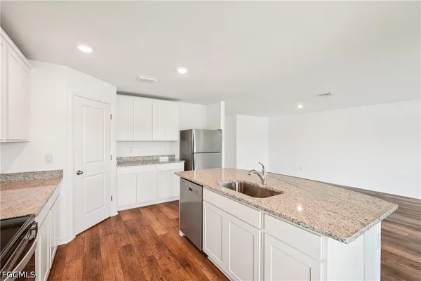 a kitchen with a sink dishwasher a stove and white cabinets with wooden floor