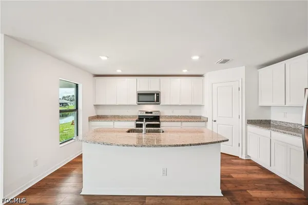 a view of kitchen with kitchen island stainless steel appliances a sink and a stove