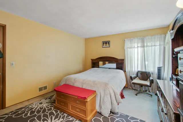 a bedroom with a large bed and a flat tv screen on dresser