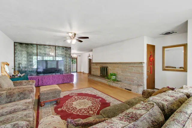 a living room with furniture hard wood floor and a floor to ceiling window