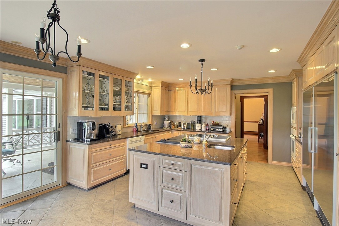 6715 Eagle Road Willoughby, OH 44094 - Photo 7 of 22 Kitchen with an island with sink, sink, a chandelier, tasteful backsplash, and decorative light fixtures