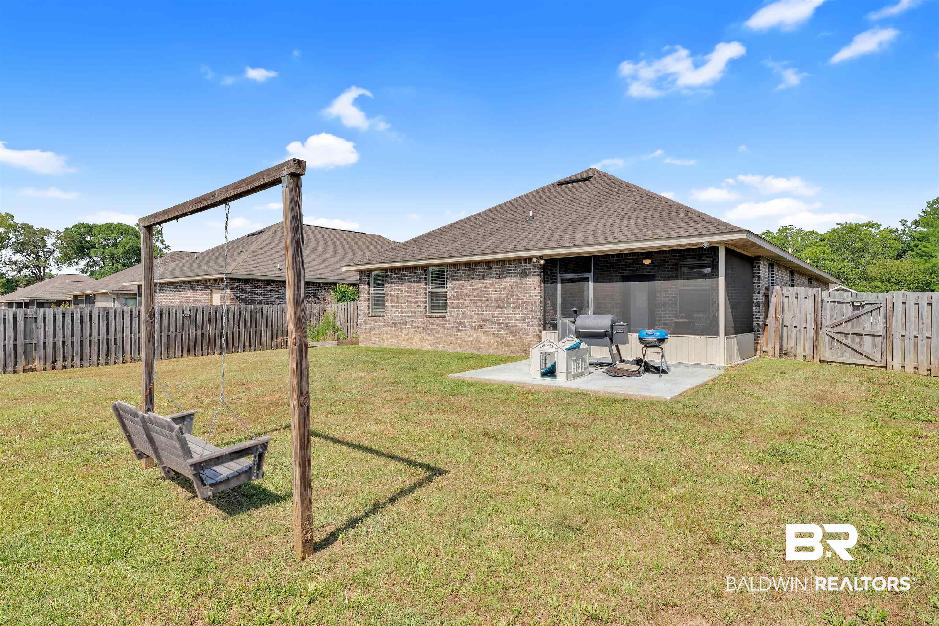 22565 Nana Loop East Silverhill, AL 36576 - Photo 23 of 26 Rear view of house with a fenced backyard, a sunroom, a patio area, and a lawn