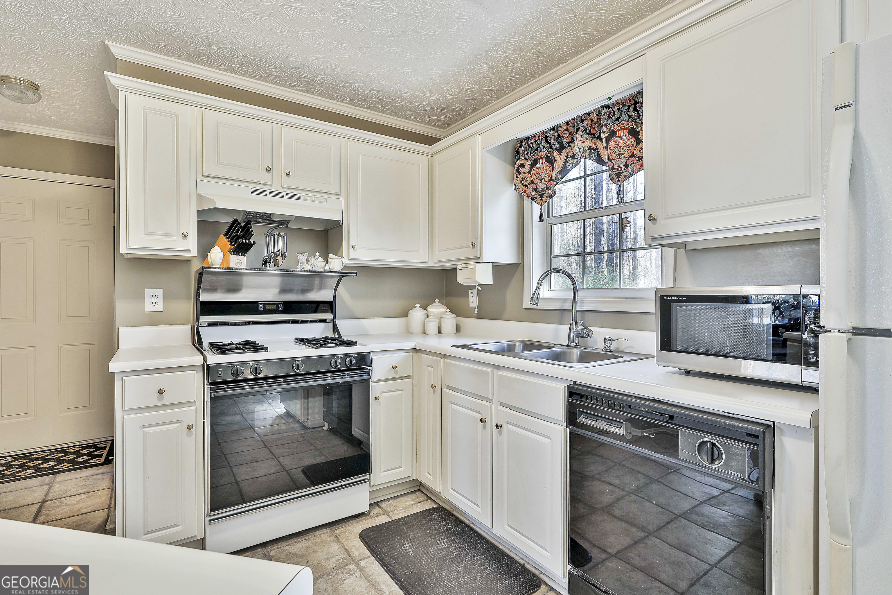 809 Lora Smith Road Newnan, GA 30265 - Photo 16 of 40 a kitchen with cabinets stainless steel appliances a sink and a stove