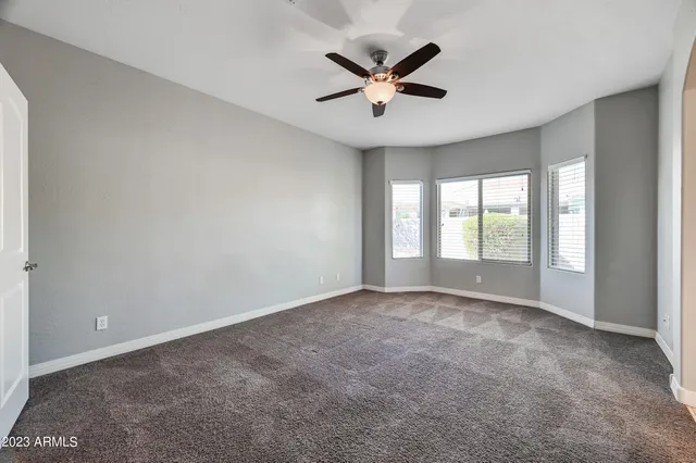 an empty room with windows and ceiling fan
