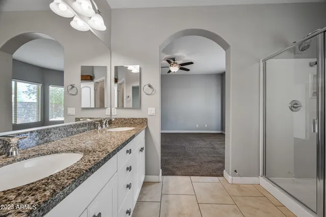 a bathroom with a granite countertop sink a large mirror and a shower