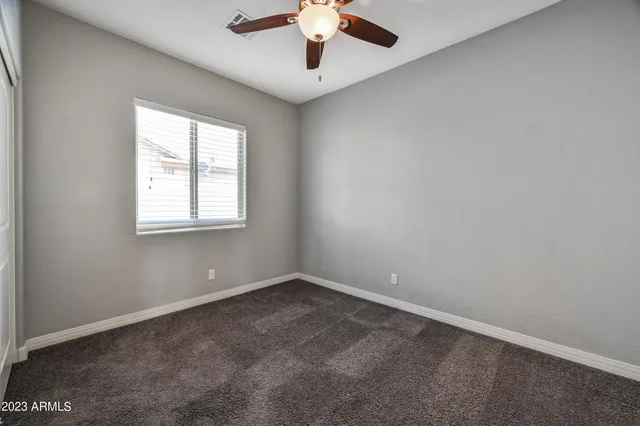 an empty room with a chandelier fan and windows