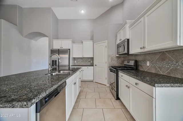 a kitchen with stainless steel appliances granite countertop a sink stove and cabinets