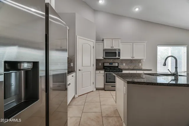 a kitchen with stainless steel appliances granite countertop a stove a sink and a refrigerator