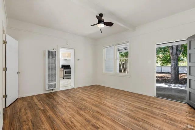 a view of empty room with wooden floor and fan