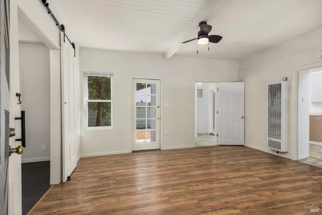a view of an empty room with wooden floor and a window