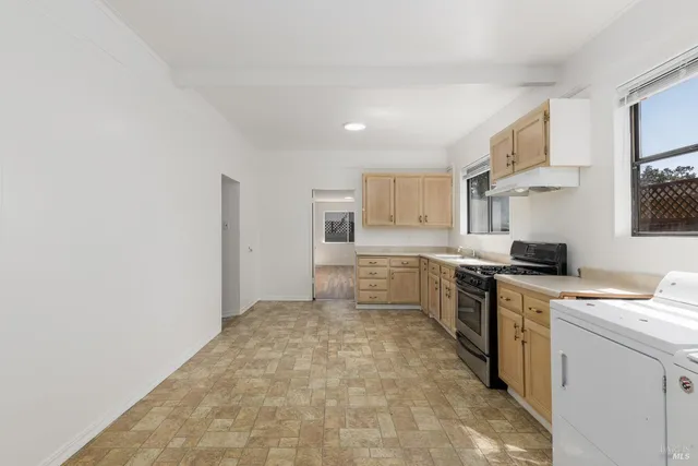 a large white kitchen with granite countertop a stove a sink dishwasher and a refrigerator