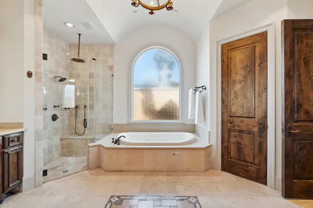 a spacious bathroom with a tub a mirror and shower